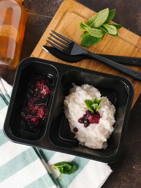 Risotto with wild berries served on black plate with knife and fork