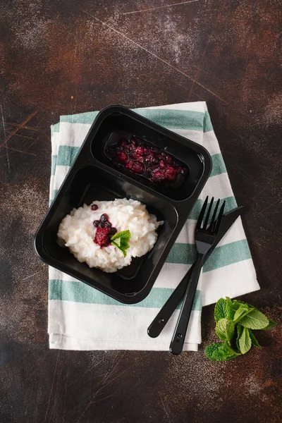 Risotto with wild berries served on black plate with knife and fork
