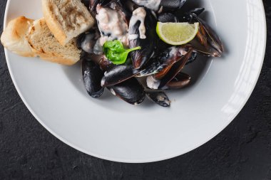 Beyaz tabakta servis edilen haşlanmış midyeler.