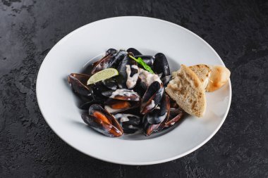 Beyaz tabakta servis edilen haşlanmış midyeler.