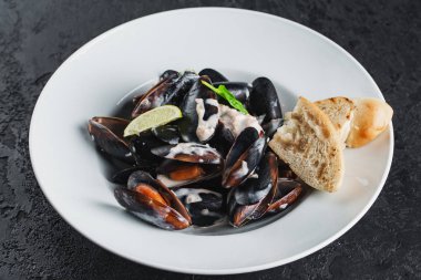 Beyaz tabakta servis edilen haşlanmış midyeler.