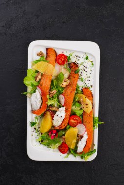 Krem peynirli turuncu kabaklar ve beyaz tabakta sebzeler.