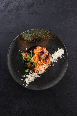 Siyah tabakta parmesan peynirli midyeli ve ahtapotlu deniz ürünleri pilavı. 