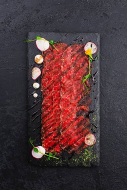 İnce dilimlenmiş çiğ sığır filetosunun siyah tabağı. 