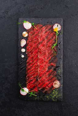 İnce dilimlenmiş çiğ sığır filetosunun siyah tabağı. 