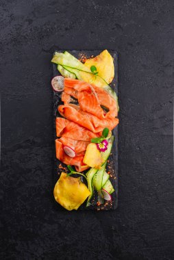 Kesilmiş mangolarla dilimlenmiş siyah somon tabağı. 