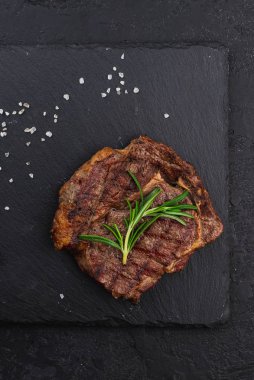 Biberiye dalı siyah tabakta servis edilen bifteğin üst görüntüsü.