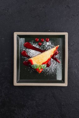 Siyah tabakta naneli ve çilekli reçelli klasik cheesecake. 