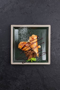 Rus krepleri ve siyah tabakta çikolata şurubu. 