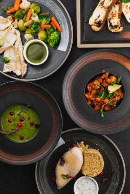 Siyah arka planda siyah tabaklarda lezzetli yemekler.