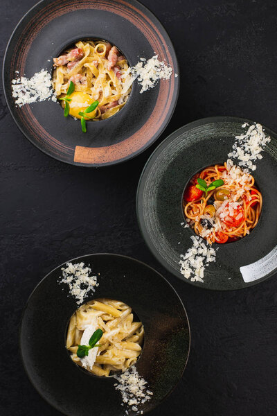 set of black plates with different Italian pasta with cheese 
