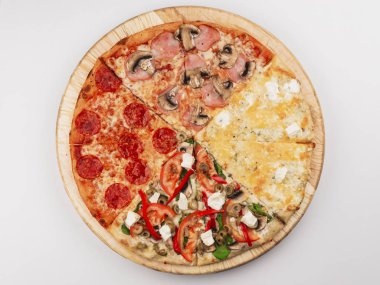Slices of different Italian traditional pizza with bacon, pepperoni sausages, olives, mushrooms and cheese on wooden plate