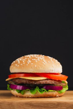  Domatesli hamburger, peynir, salatalık ve siyah arka planda marul. 