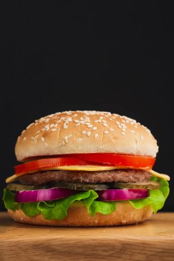  Domatesli hamburger, peynir, salatalık ve siyah arka planda marul. 