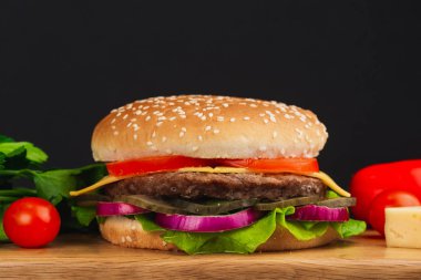 Yakın çekim, domatesli lezzetli hamburger, peynir, salatalık ve marul.