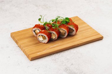 İçinde havyar, krem peynir ve avokado olan gurme suşi, ahşap tahtada.