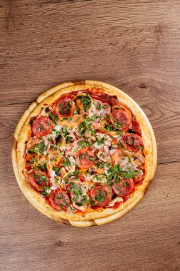 Ahşap masa arkasında sosis ve domatesli taze pişmiş lezzetli pizza.