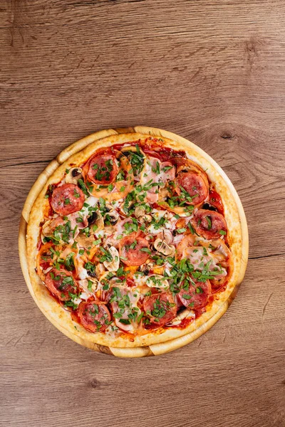 Ahşap masa arkasında sosis ve domatesli taze pişmiş lezzetli pizza.