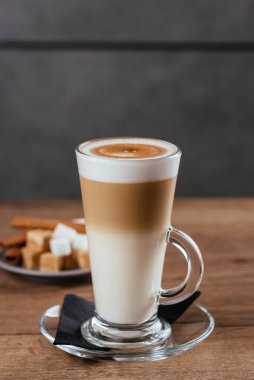 Latte cam bardak beyaz ve kahverengi şeker dilimleri ahşap masa arkasında