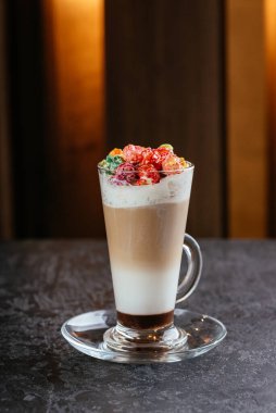 Masa arkasında renkli şekerler olan kapuçino bardağı.