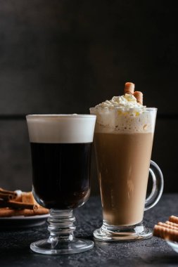 siyah espresso fincanı kapuçino ile çırpılmış krema ve kırsal masa üzerinde tatlı çubuklar