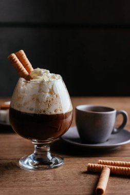 siyah espresso fincanı kapuçino ile çırpılmış krema ve kırsal masa üzerinde tatlı çubuklar