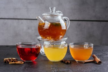 Deniz dikenli, cam bardaklı, ahududulu ve tarçınlı, sade arkaplanda kakule olan sıcak çay demliği.