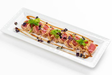 Baharatlı susamlı et, otlar, yeşiller ve beyaz tabakta sos. 