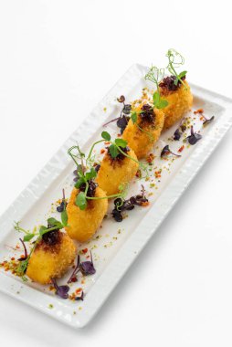 Üzümlü kızarmış Camembert dilimleri, ahududu sosu ve beyaz tabakta yeşillikler.