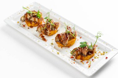 Patatesli kanepe dilimleri ızgara füme yılan balığı ve beyaz tabakta sos.