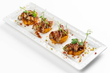 Patatesli kanepe dilimleri ızgara füme yılan balığı ve beyaz tabakta sos.