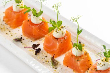 beyaz tabak somon dilimlenmiş krem peynirli ve yeşillikli 