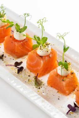 beyaz tabak somon dilimlenmiş krem peynirli ve yeşillikli 