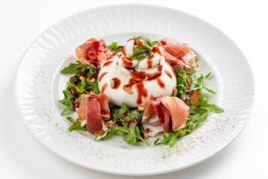 İtalyan şarküteri salatası, burrata peyniri ve beyaz tabakta parma jambonu dilimleri. 