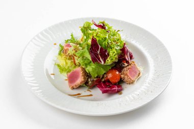 Lezzetli ton balığı dilimleri, yeşiller ve domatesli beyaz tabakta salata