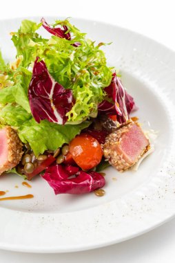 Lezzetli ton balığı dilimleri, yeşiller ve domatesli beyaz tabakta salata