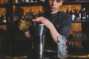 Genç barmen buzlu ve limonlu klasik alkol içeceği yapıyor.