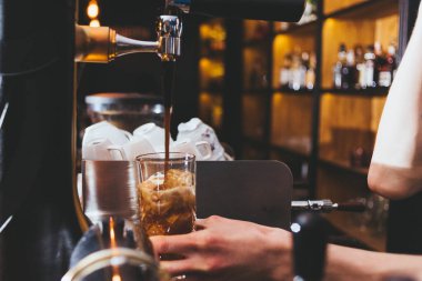 Genç barmen buzlu ve limonlu klasik alkol içeceği yapıyor.