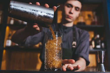 Genç barmen buzlu ve limonlu klasik alkol içeceği yapıyor.