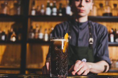 Genç barmen buzlu ve limonlu klasik alkol içeceği yapıyor.