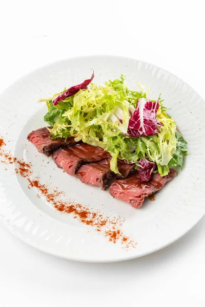 Italian colored salad with beef slices, greens and red peppers on white plate