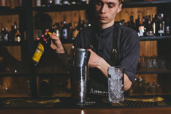 年轻的酒保用冰块和柠檬片制作经典的酒精饮料 — 图库照片