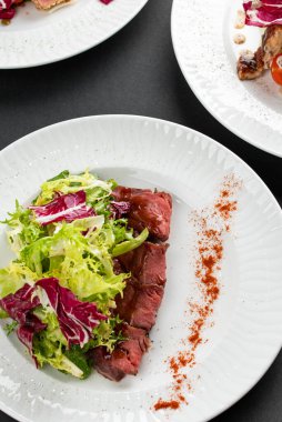 sığır eti dilimli renkli salata, yeşiller ve kırsal peçetede beyaz tabakta kırmızı biber.