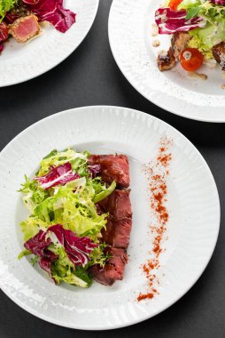 sığır eti dilimli renkli salata, yeşiller ve kırsal peçetede beyaz tabakta kırmızı biber.
