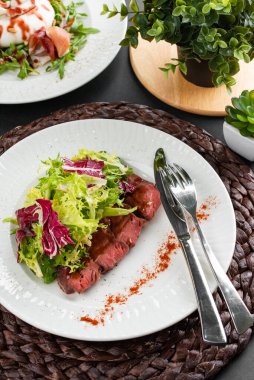 sığır eti dilimli renkli salata, yeşiller ve kırsal peçetede beyaz tabakta kırmızı biber.