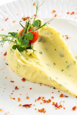 Domates dilimiyle süslenmiş tereyağlı patates püresi ve beyaz tabakta kırmızı biber. 