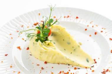 Domates dilimiyle süslenmiş tereyağlı patates püresi ve beyaz tabakta kırmızı biber. 