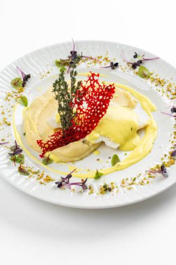 Patates püresi ve krema soslu fırında balık fileto otlar ve beyaz tabakta kırmızı kraker. 