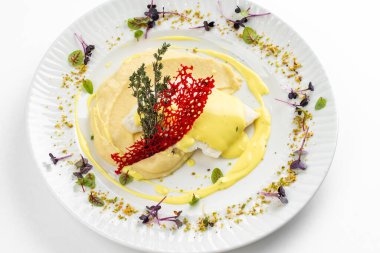 Patates püresi ve krema soslu fırında balık fileto otlar ve beyaz tabakta kırmızı kraker. 