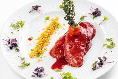 Kırmızı sosun altında kızarmış ördek filetosu ve beyaz tabakta domates. 